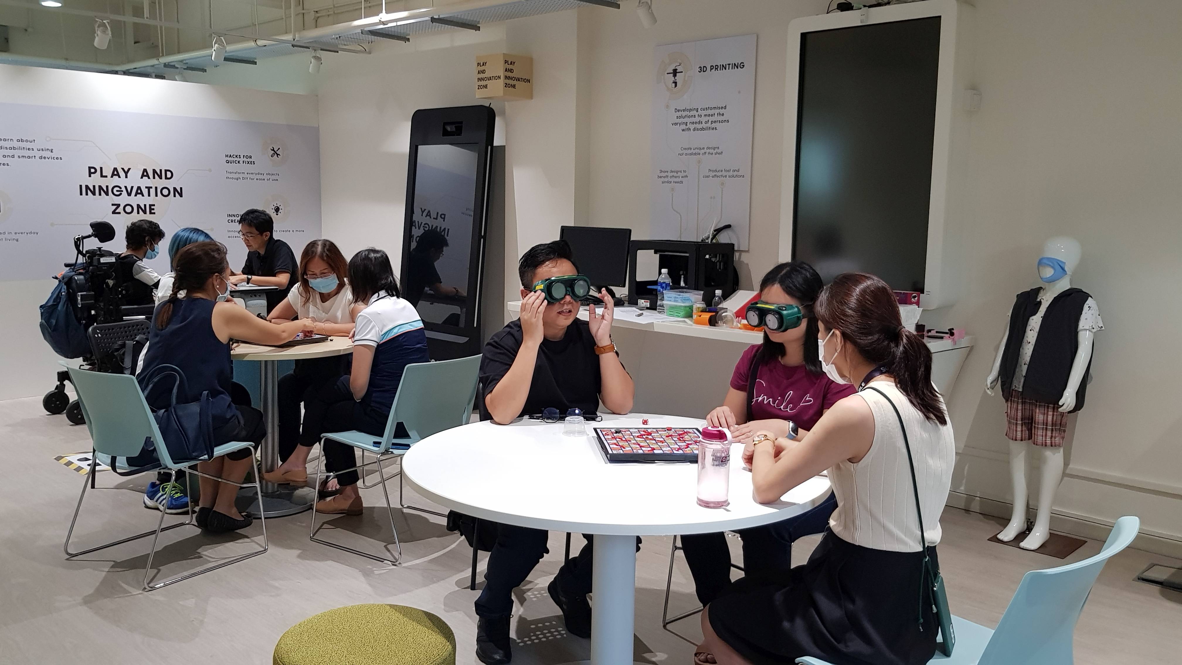 Participants using low vision simulation goggles to try out the modified board games.